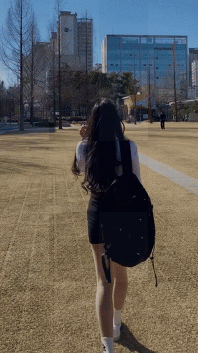 A Woman With A Black Backpack Is Walking In A Field GIF
