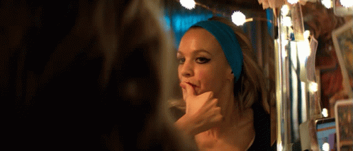 A Woman With A Blue Headband On Her Head Looks At Herself In A Mirror GIF