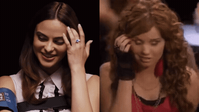 A Woman With A Blue Ring On Her Finger Is Smiling Next To A Woman With Curly Hair GIF