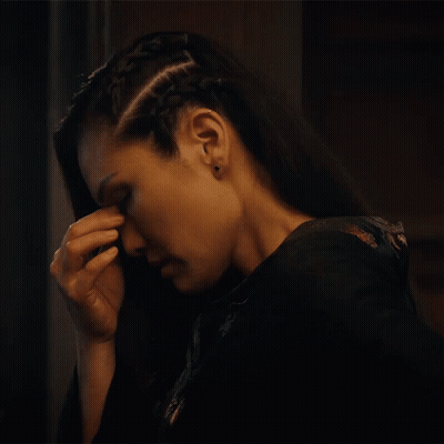 A Woman With A Braid In Her Hair Has Her Hand On Her Forehead GIF