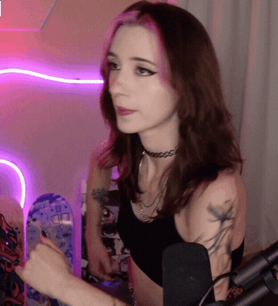 A Woman With A Choker On Her Neck Is Standing In Front Of A Microphone GIF