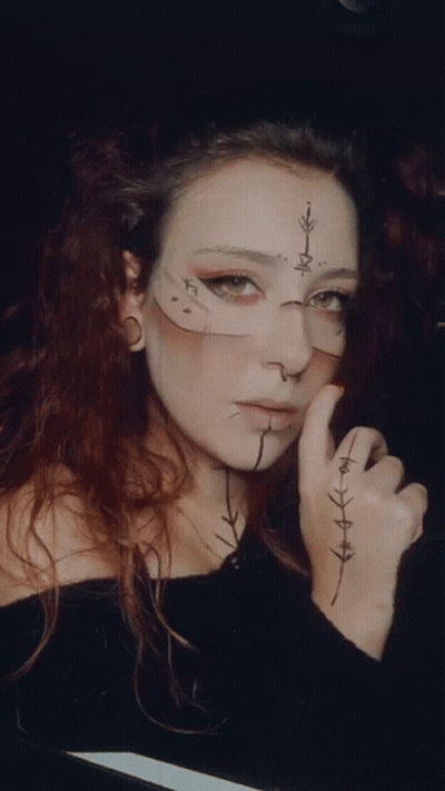 A Woman With A Cross On Her Face Has A Tattoo On Her Hand GIF