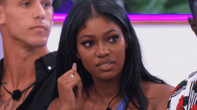A Woman With A Diamond Ring On Her Finger Is Sitting In Front Of Two Men GIF