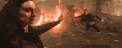 A Woman With A Flame On Her Face Is Standing In Front Of A Burning Building GIF