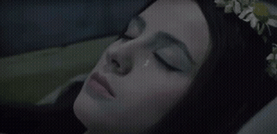 A Woman With A Flower Crown On Her Head Is Laying In Bed With Her Eyes Closed GIF