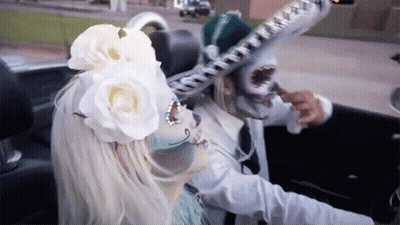 A Woman With A Flower In Her Hair Is Driving A Car GIF