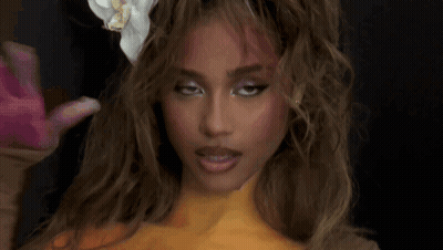 A Woman With A Flower In Her Hair Is Getting Her Hair Done . GIF