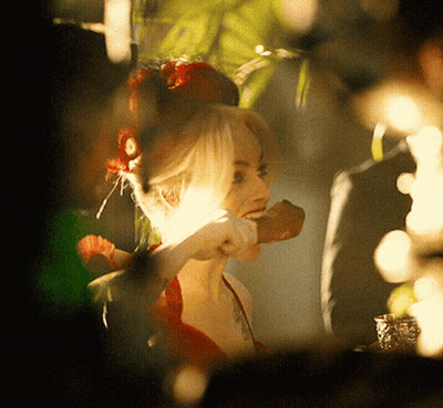 A Woman With A Flower In Her Hair Is Holding A Piece Of Food GIF