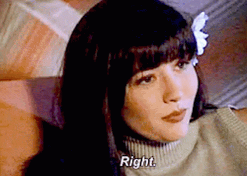 A Woman With A Flower In Her Hair Is Sitting On A Couch . GIF