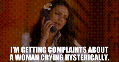 A Woman With A Flower In Her Hair Is Talking On A Phone . GIF