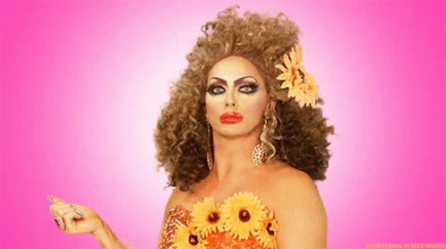 A Woman With A Flower In Her Hair Is Wearing A Dress With Flowers On It GIF