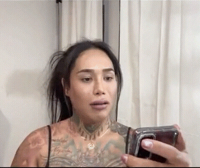 A Woman With A Lot Of Tattoos Is Taking A Selfie With Her Cell Phone . GIF