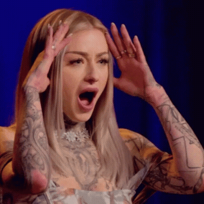 A Woman With A Lot Of Tattoos On Her Arms Is Making A Surprised Face With Her Mouth Open . GIF