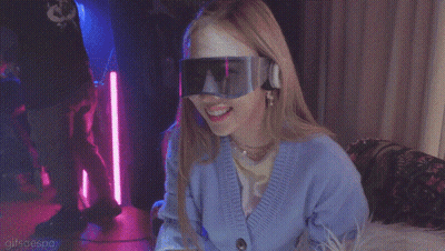 A Woman With A Mask On Her Face Is Wearing A Blue Cardigan And Goggles GIF