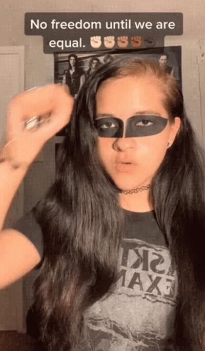 A Woman With A Mask On Her Face Is Wearing A T-Shirt That Says Maxf GIF