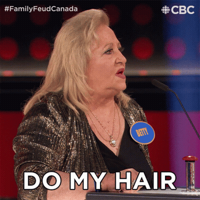 A Woman With A Name Tag That Says Betty Stands In Front Of A Microphone And Says " Do My Hair " GIF