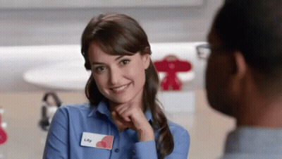 A Woman With A Name Tag That Says Lily Is Smiling At A Man GIF