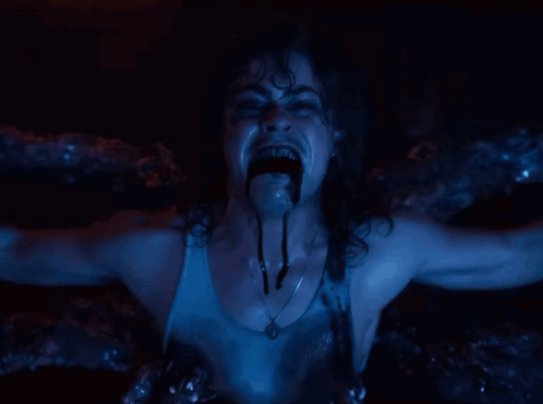 A Woman With A Necklace Around Her Neck Is Screaming In A Dark Room GIF
