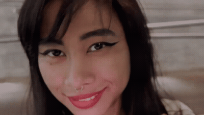 A Woman With A Nose Ring And Red Lipstick Is Smiling For The Camera . GIF