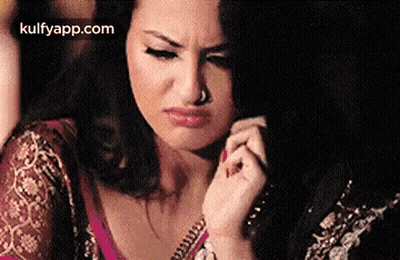 A Woman With A Nose Ring Is Making A Funny Face While Holding Her Hair . GIF
