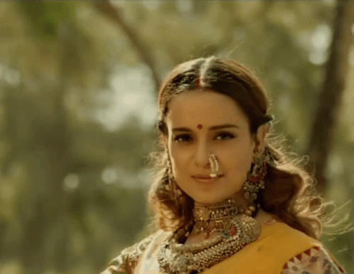 A Woman With A Nose Ring Is Wearing A Yellow Sari GIF