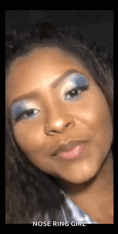 A Woman With A Nose Ring Is Wearing Blue Eye Shadow . GIF
