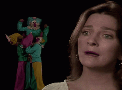 A Woman With A Nose Ring Looks At A Group Of Clowns On Stilts GIF