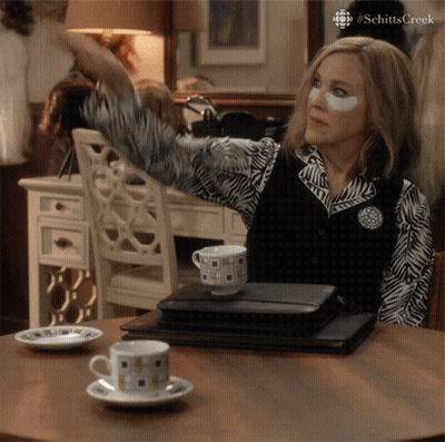 A Woman With A Patch On Her Eye Is Sitting At A Table With A Cup Of Coffee On It GIF