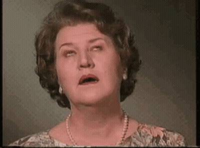 A Woman With A Pearl Necklace Is Making A Funny Face . GIF