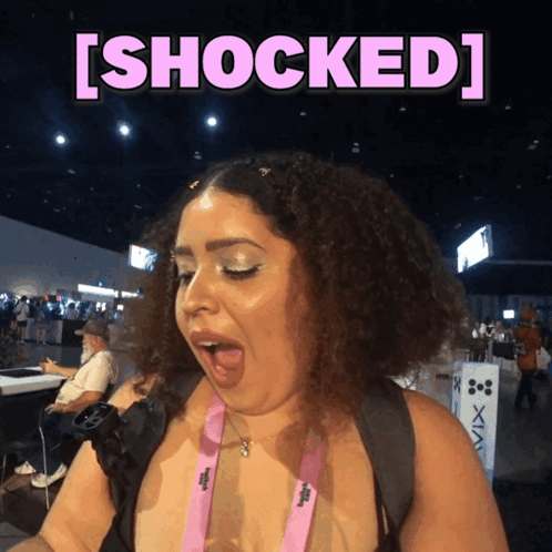 A Woman With A Pink Lanyard Around Her Neck Is Shocked GIF