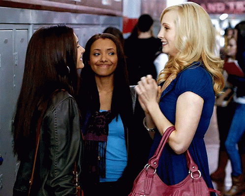 A Woman With A Pink Purse Is Talking To Two Other Women In A Hallway GIF