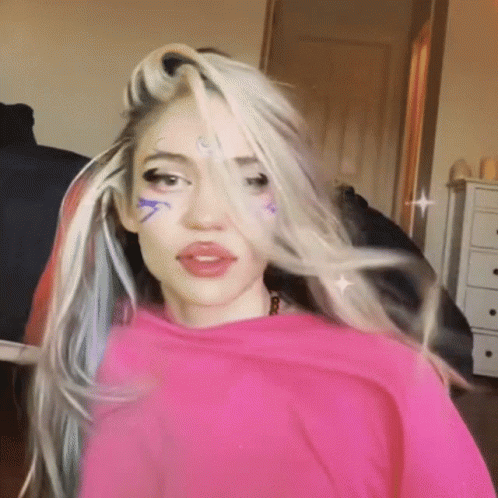 A Woman With A Pink Shirt On Has A Tattoo On Her Forehead That Says ' A ' GIF