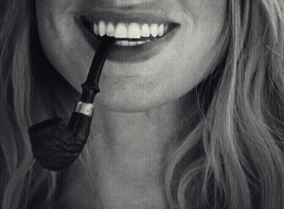 A Woman With A Pipe In Her Mouth And A Smile On Her Face GIF