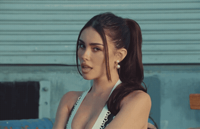 A Woman With A Ponytail And Pearl Earrings Looks To The Side GIF