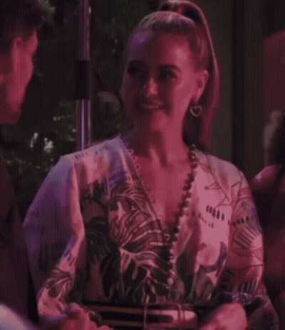 A Woman With A Ponytail Is Smiling And Wearing A Floral Shirt GIF