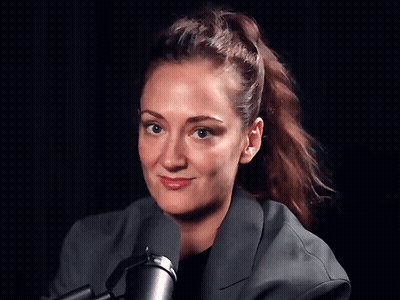 A Woman With A Ponytail Is Standing In Front Of A Microphone GIF