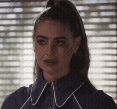 A Woman With A Ponytail Is Wearing A Blue Jacket With White Trim GIF