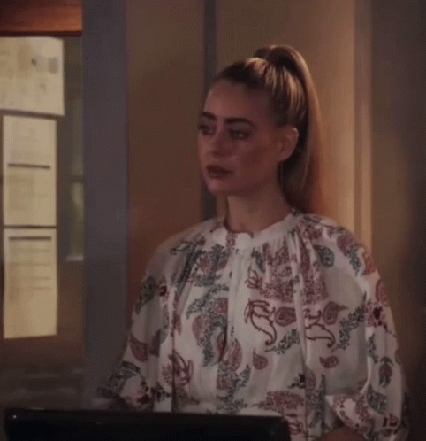A Woman With A Ponytail Is Wearing A Floral Top GIF