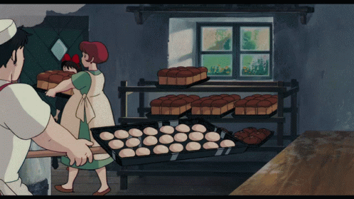 A Woman With A Red Bow On Her Head Is Standing Next To A Man In A Bakery Holding A Loaf Of Bread GIF