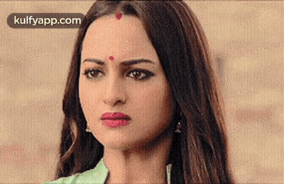 A Woman With A Red Dot On Her Forehead Is Making A Face . GIF