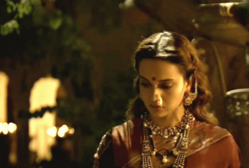 A Woman With A Red Dot On Her Forehead Is Wearing A Necklace GIF