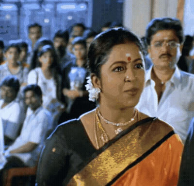 A Woman With A Red Dot On Her Forehead Stands In A Crowd Of People GIF