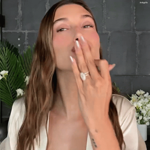 A Woman With A Ring On Her Finger Is Blowing A Kiss At The Camera GIF