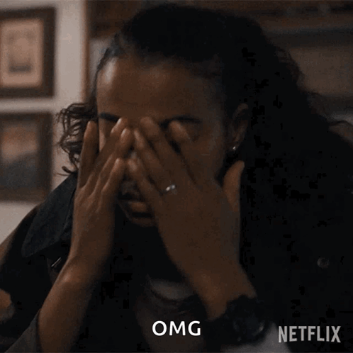 A Woman With A Ring On Her Finger Is Covering Her Face With Her Hands And A Netflix Logo Is Behind Her GIF