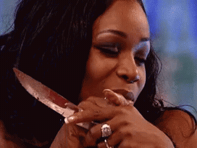 A Woman With A Ring On Her Finger Is Holding A Knife In Her Hand . GIF