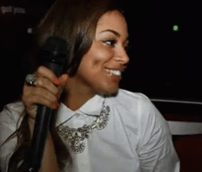 A Woman With A Ring On Her Finger Is Holding A Microphone And Smiling GIF