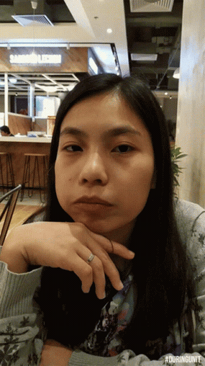 A Woman With A Ring On Her Finger Is Sitting In Front Of A Sandwich Shop GIF