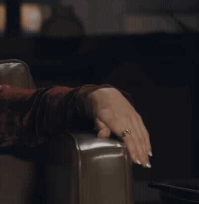 A Woman With A Ring On Her Finger Is Sitting On A Chair GIF