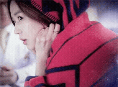 A Woman With A Ring On Her Finger Is Wearing A Red And Blue Sweater GIF