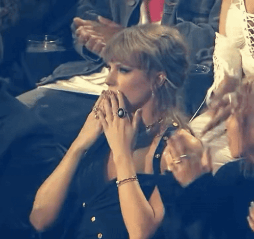A Woman With A Ring On Her Finger Sitting In A Crowd GIF